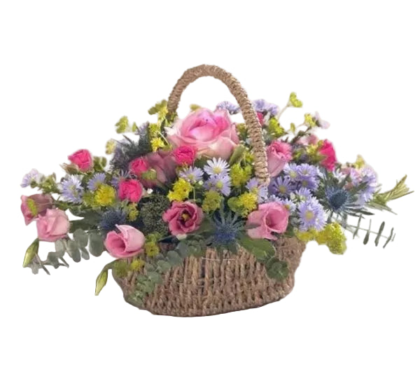 Wicker basket filled with a colorful arrangement of flowers on a wooden surface.